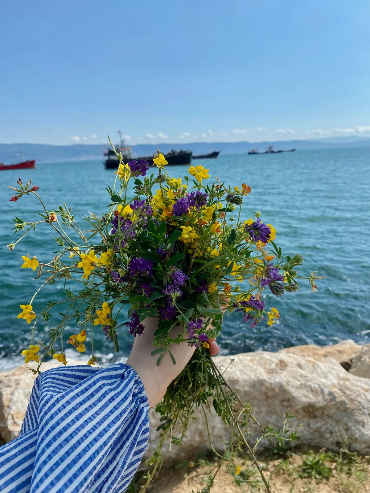 Wildflower bouquet held beside the sea