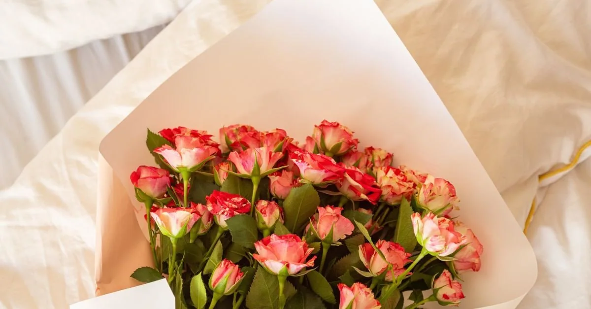 Ramo de rosas ramificadas rosas envuelto en papel rosa suave